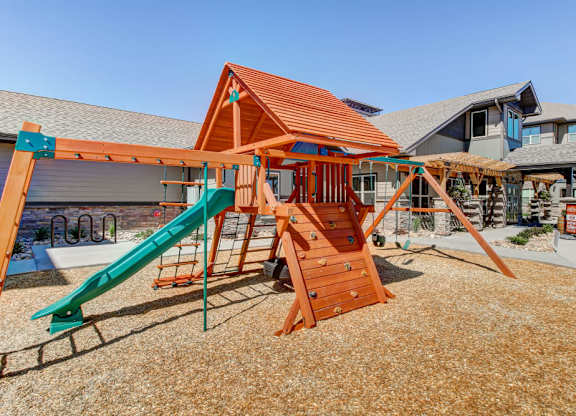 A playground with a green slide and a wooden structure.