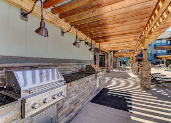 A patio with a grill and a wooden ceiling.