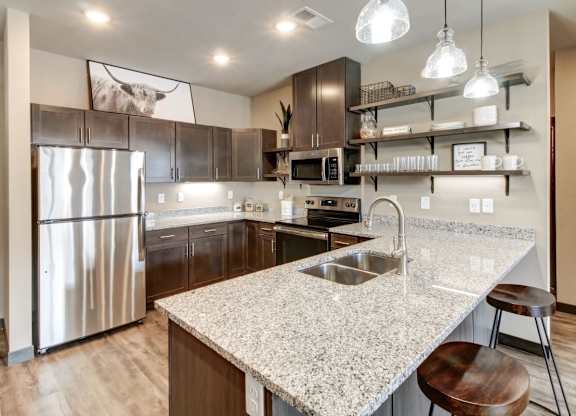 A modern kitchen with granite countertops and stainless steel appliances.