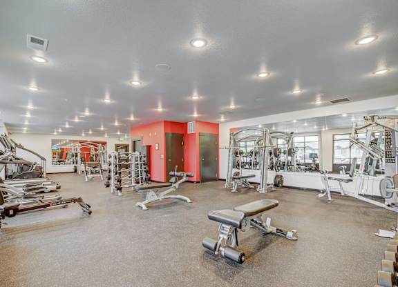 A gym with a variety of equipment including treadmills, weights, and exercise machines.