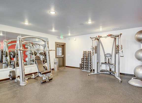 A gym with a variety of equipment including weights and a leg press machine.
