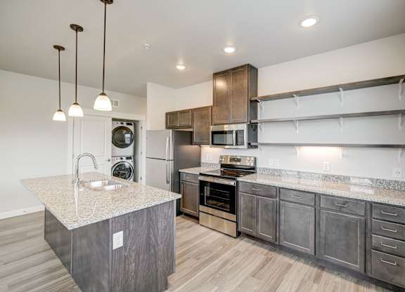 A modern kitchen with a granite countertop and stainless steel appliances.