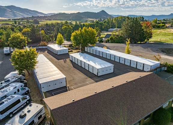 A parking lot with a mountainous background and a building with a brown roof.