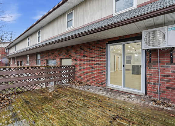 A red brick house with a white door and a brown fence.
