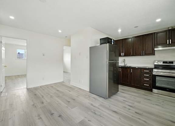 A kitchen with a refrigerator, oven, and cabinets.
