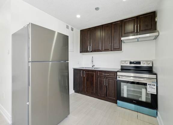 A modern kitchen with a stainless steel refrigerator and dark brown cabinets.