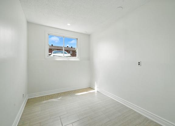 A room with a window and a white wall.