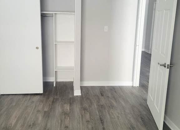 A white door is open to a room with a grey floor.