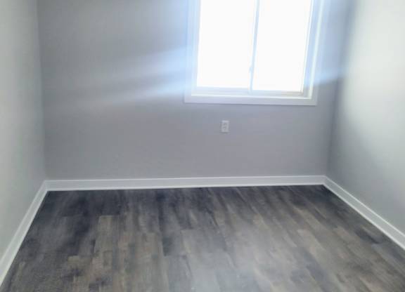 A room with a window and wooden flooring.