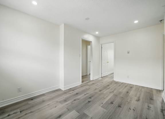 A room with wooden flooring and white walls.