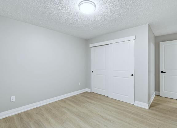 A white room with a sliding door and a wooden floor.