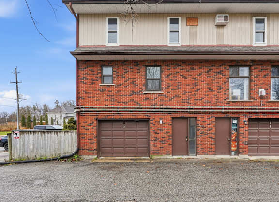 A red brick building with a white roof and a brown garage door.