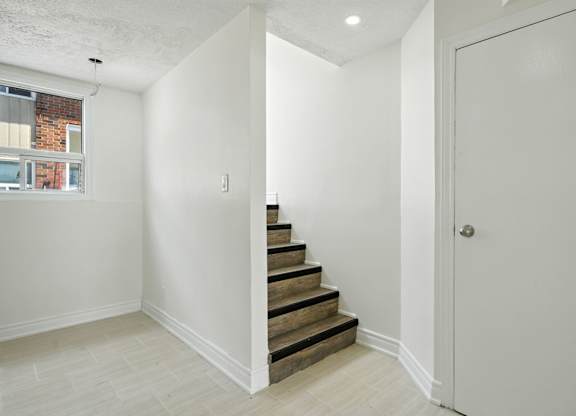 A white room with a staircase leading to the next floor.