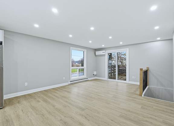 A spacious room with wooden flooring and white walls.