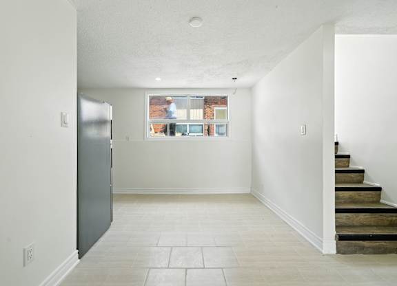 A kitchen with a refrigerator and a window with a view of a city.