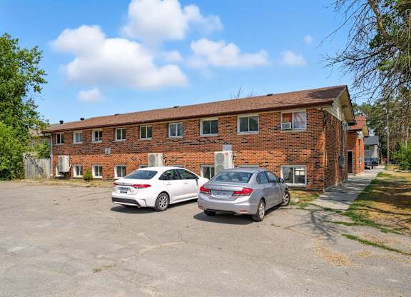 Two cars parked in front of a brick building.