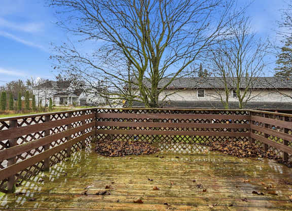 A wooden deck with a railing and a pile of leaves in the middle.
