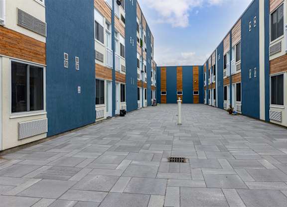 A long, narrow courtyard between two buildings with blue and white walls.