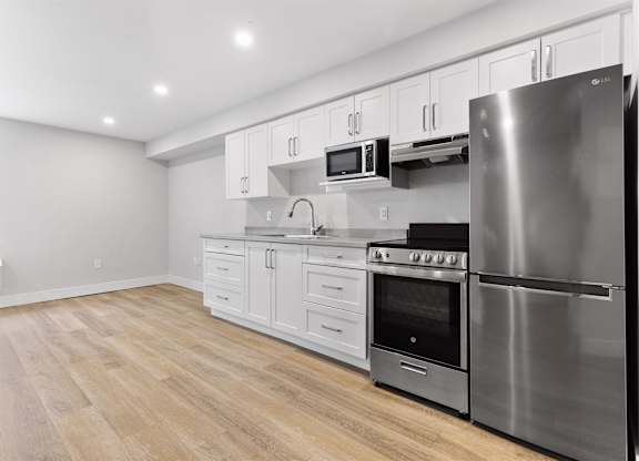 A modern kitchen with stainless steel appliances and wooden flooring.