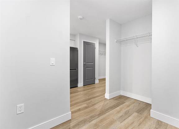 A white room with a wooden floor and a closet with a door.