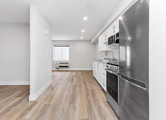 A modern kitchen with stainless steel appliances and wooden flooring.
