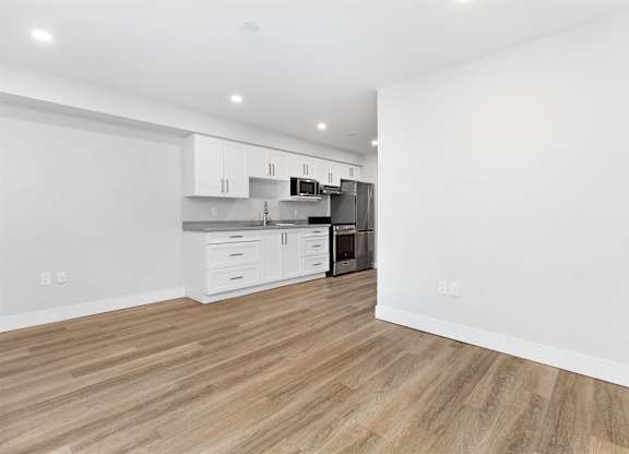 A kitchen with white cabinets and a wooden floor.