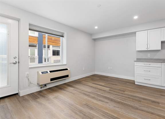 A room with a window, a radiator, and a kitchenette.
