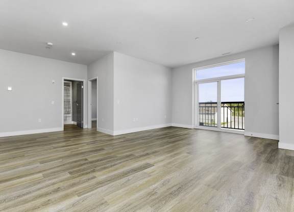 A spacious room with wooden flooring and white walls.