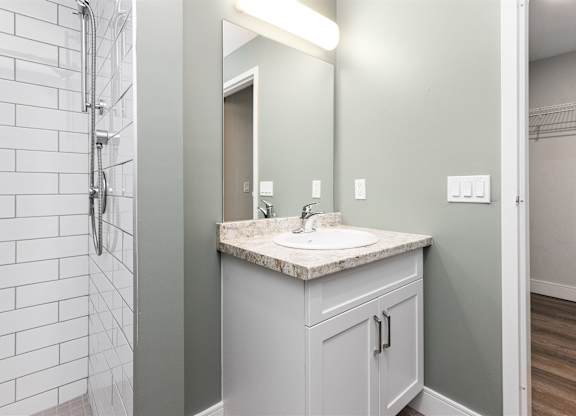 A bathroom with a marble countertop and a white tiled shower.
