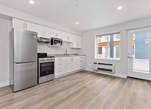 A modern kitchen with stainless steel appliances and wooden flooring.