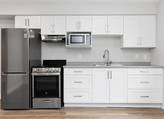 A modern kitchen with a stainless steel refrigerator, oven, and microwave.