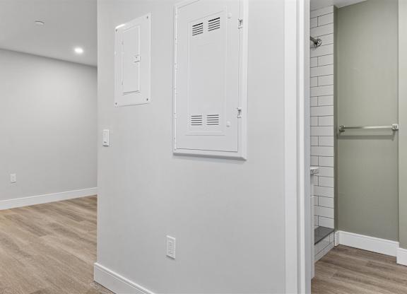 A white bathroom with wood flooring and a white door.