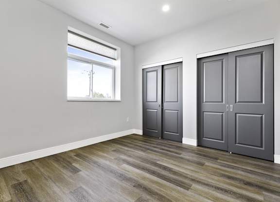 A room with wooden flooring and two grey doors.