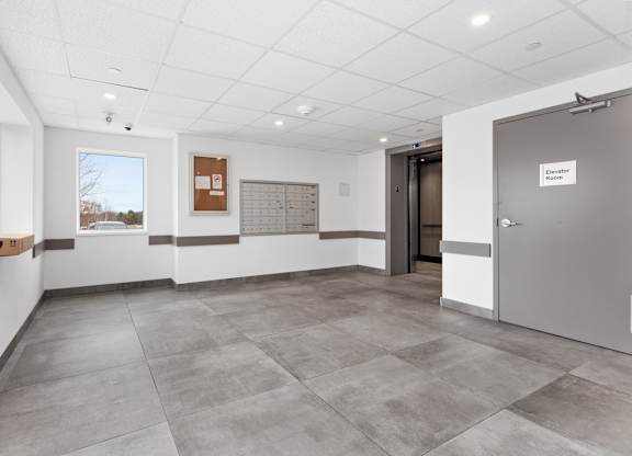 A room with a grey floor and a white ceiling with a door on the right.