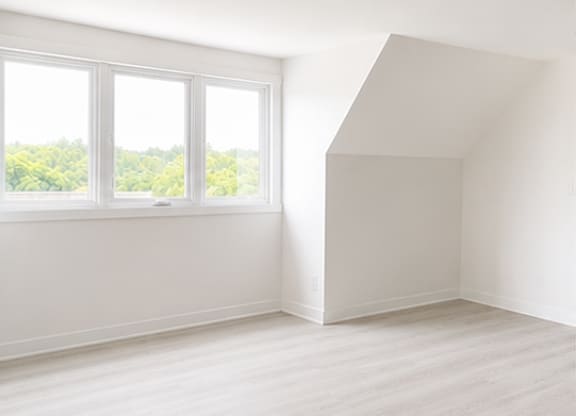 A white room with a window and a wooden floor.
