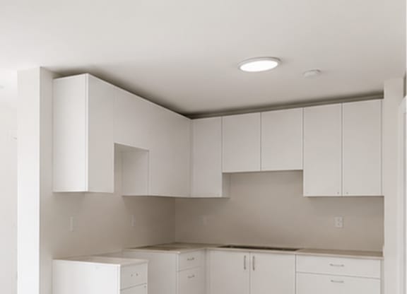 A kitchen with white cabinets and a white floor.