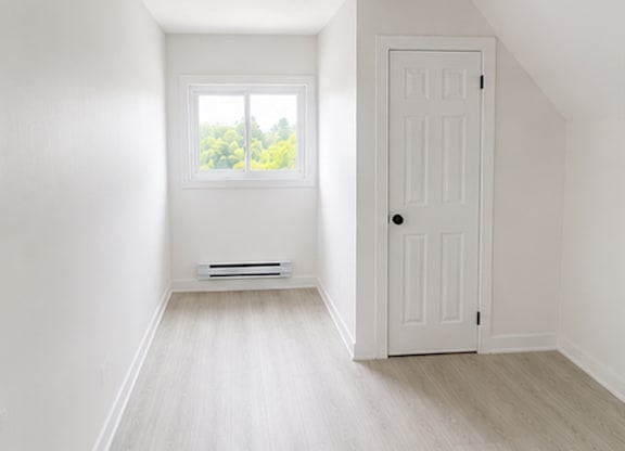 A white door is on the right side of a room with a window.