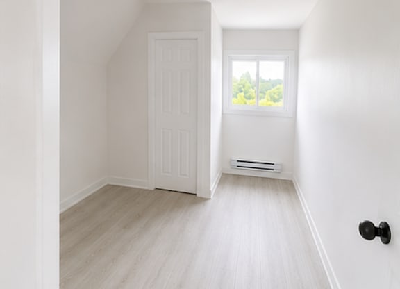 A white door is in a room with a window.