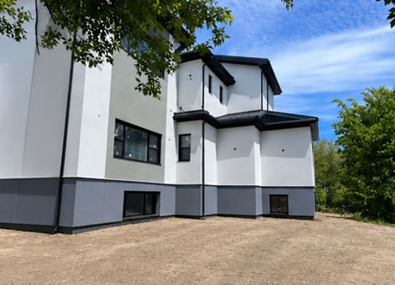 A modern building with a white and black exterior is surrounded by trees.