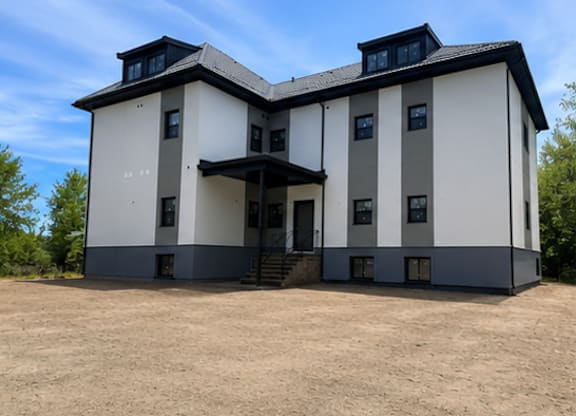 A large, two-story house with a black roof and white walls.