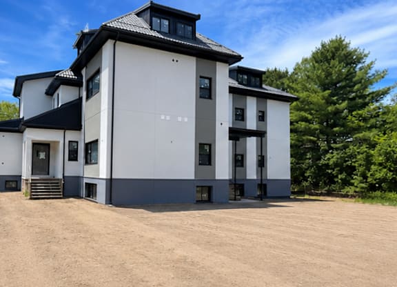 A modern two-story house with a black roof and white walls.