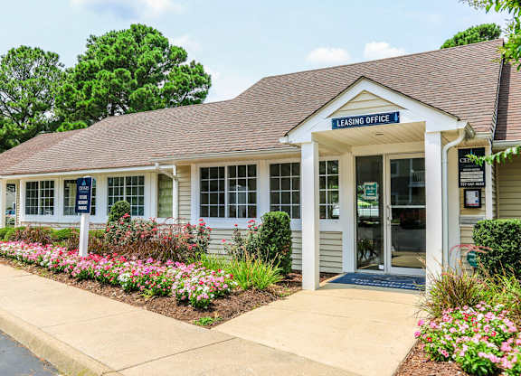 A leasing office building with a flower bed in front.