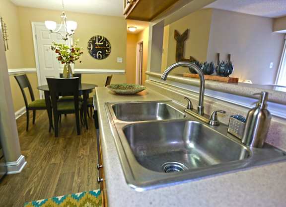 A kitchen with a large sink and a dining table with chairs.
