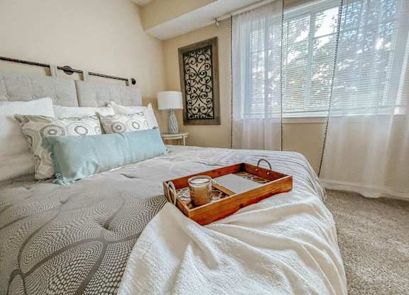 A tray with a candle and a glass sits on a bed.