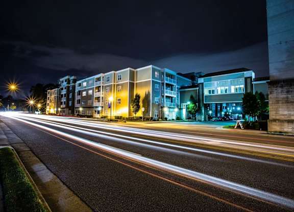 A long exposure shot of a street at night with light trails from moving vehicles.