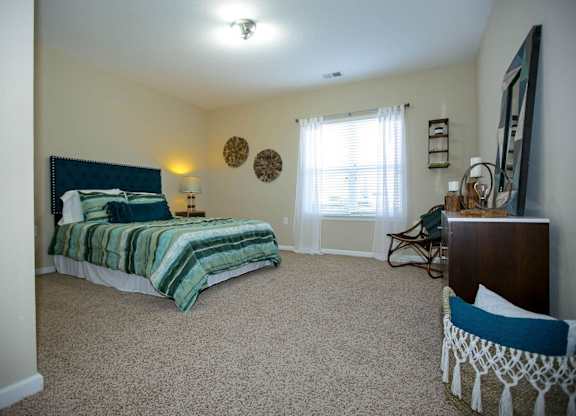 A bedroom with a bed, a chair, and a dresser.