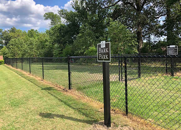 A sign that says Bark Park is on a fence.