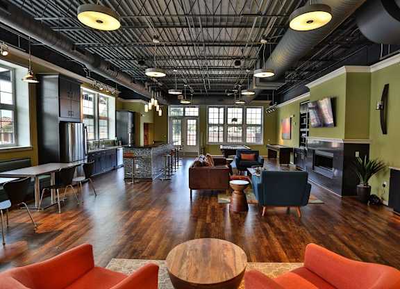 A large room with a wooden floor and a high ceiling with exposed pipes.