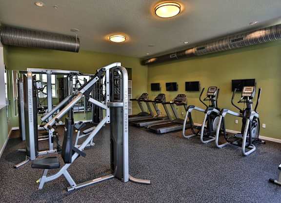 A gym with a variety of equipment including treadmills, weights, and exercise bikes.