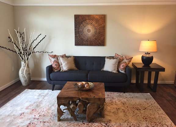 A living room with a blue couch, a wooden coffee table, and a painting on the wall.